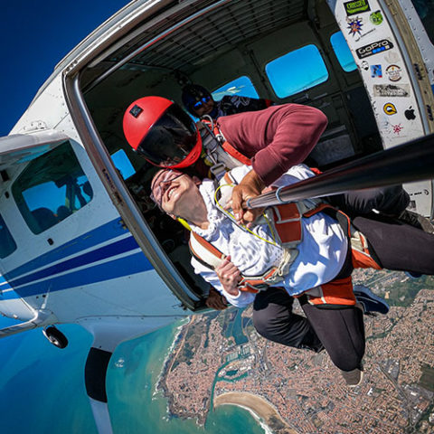 Parachute jump over a beach.