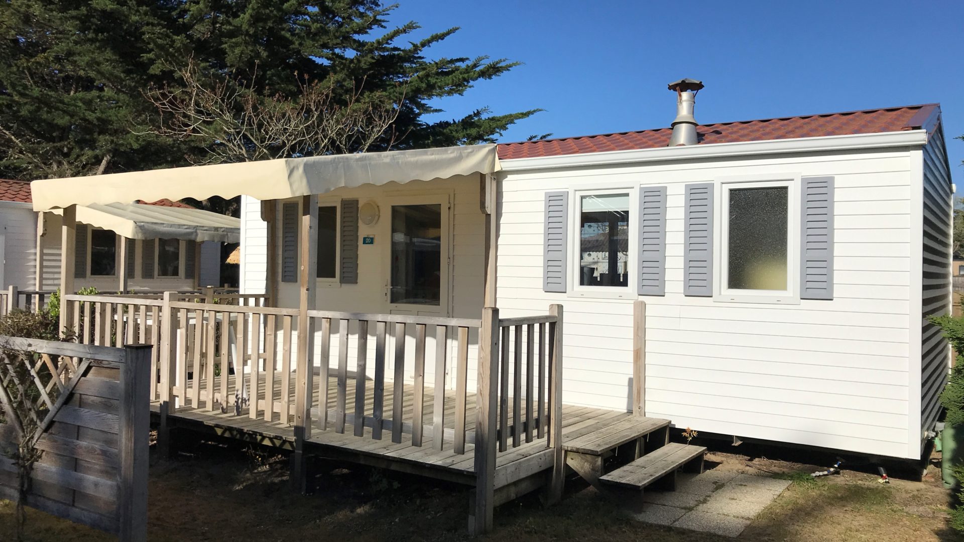 Mobil-home blanc avec terrasse en bois
