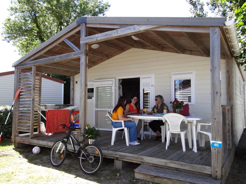 Trois personnes discutent sur terrasse en bois.