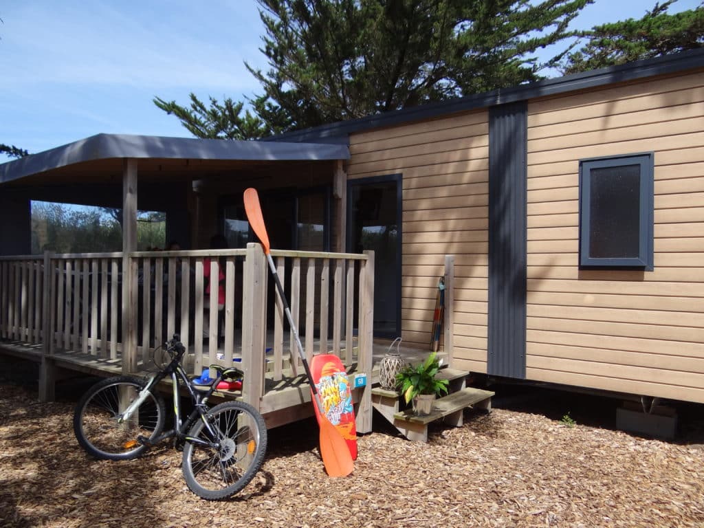 Mobil-home avec vélo et pagaie devant terrasse