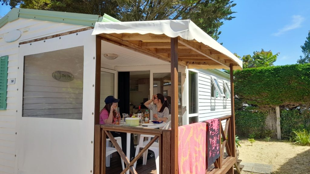 Personnes déjeunant sur la terrasse d'un mobile home.