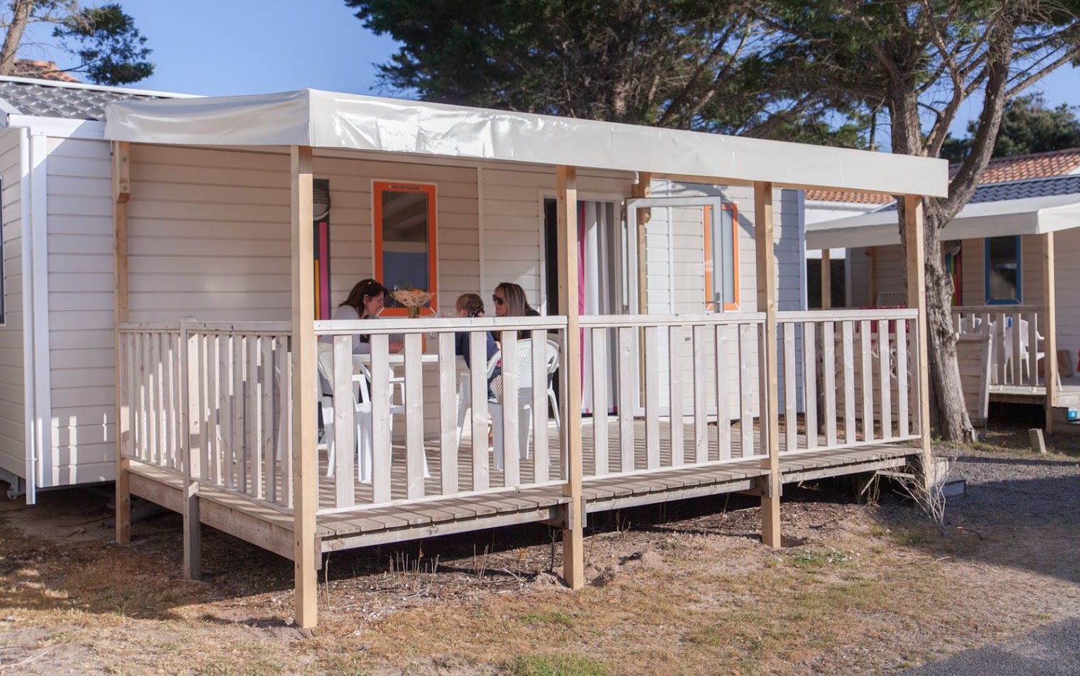 Terrasse de mobil-home avec trois personnes assises