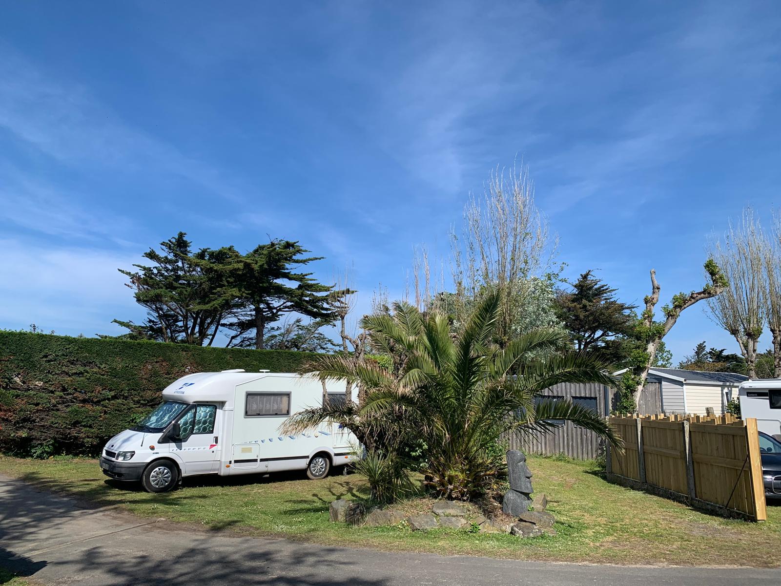 Camping-car garé dans un jardin ensoleillé.