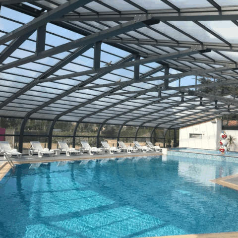 Modern indoor pool with white sun loungers.