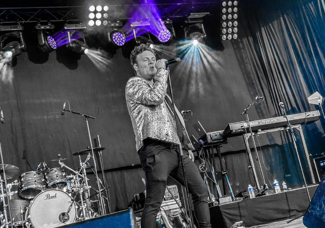 Singer on stage with drums and Yamaha keyboard.
