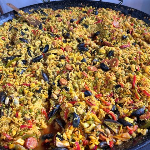 Large paella with seafood and colorful vegetables.